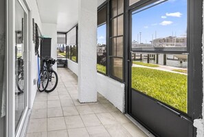 A covered outdoor area with a bicycle rack, a glass door, and a view of a marina.
