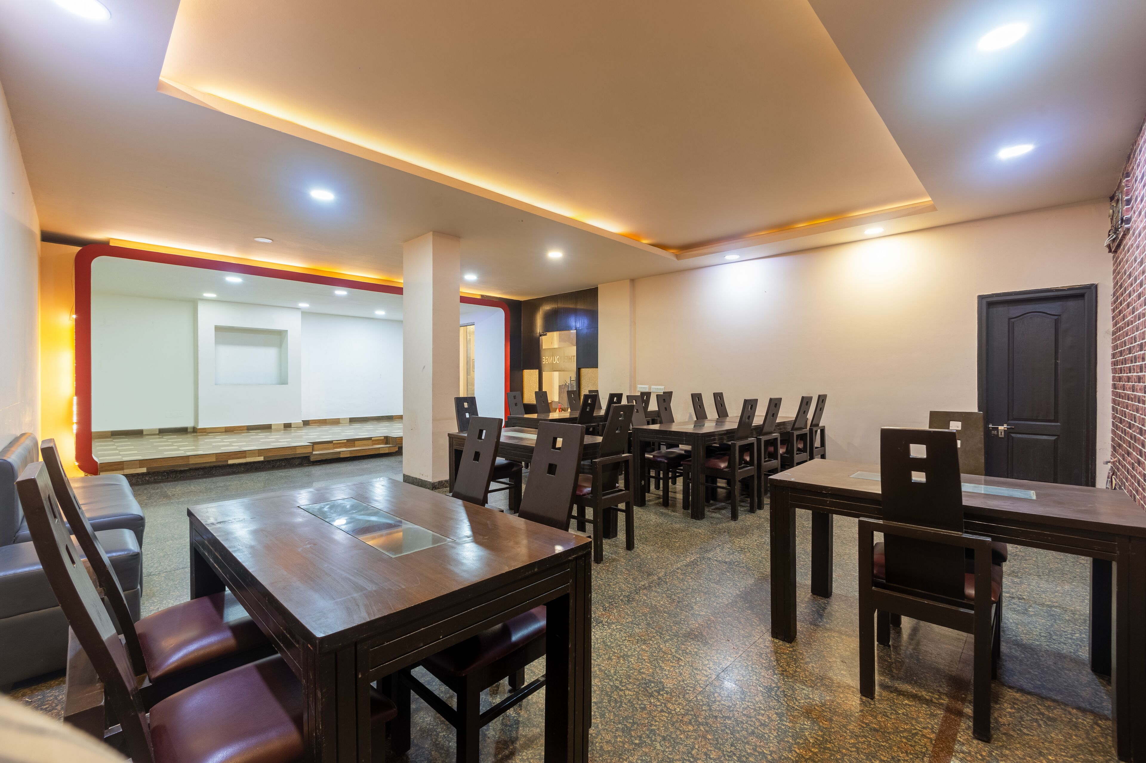 Un salón de conferencias con varias mesas y sillas, una pared de ladrillo y una puerta.
