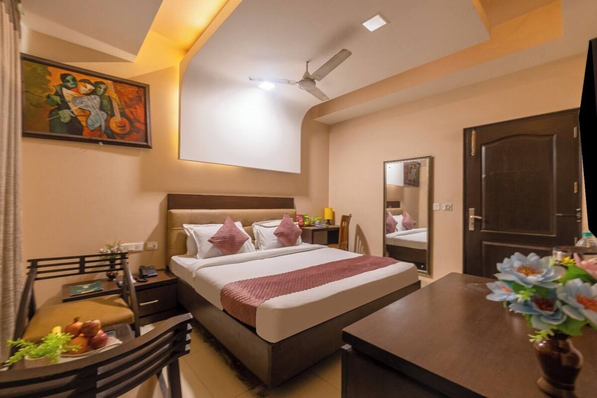 A hotel room with a bed, desk, chair, and a large mirror.