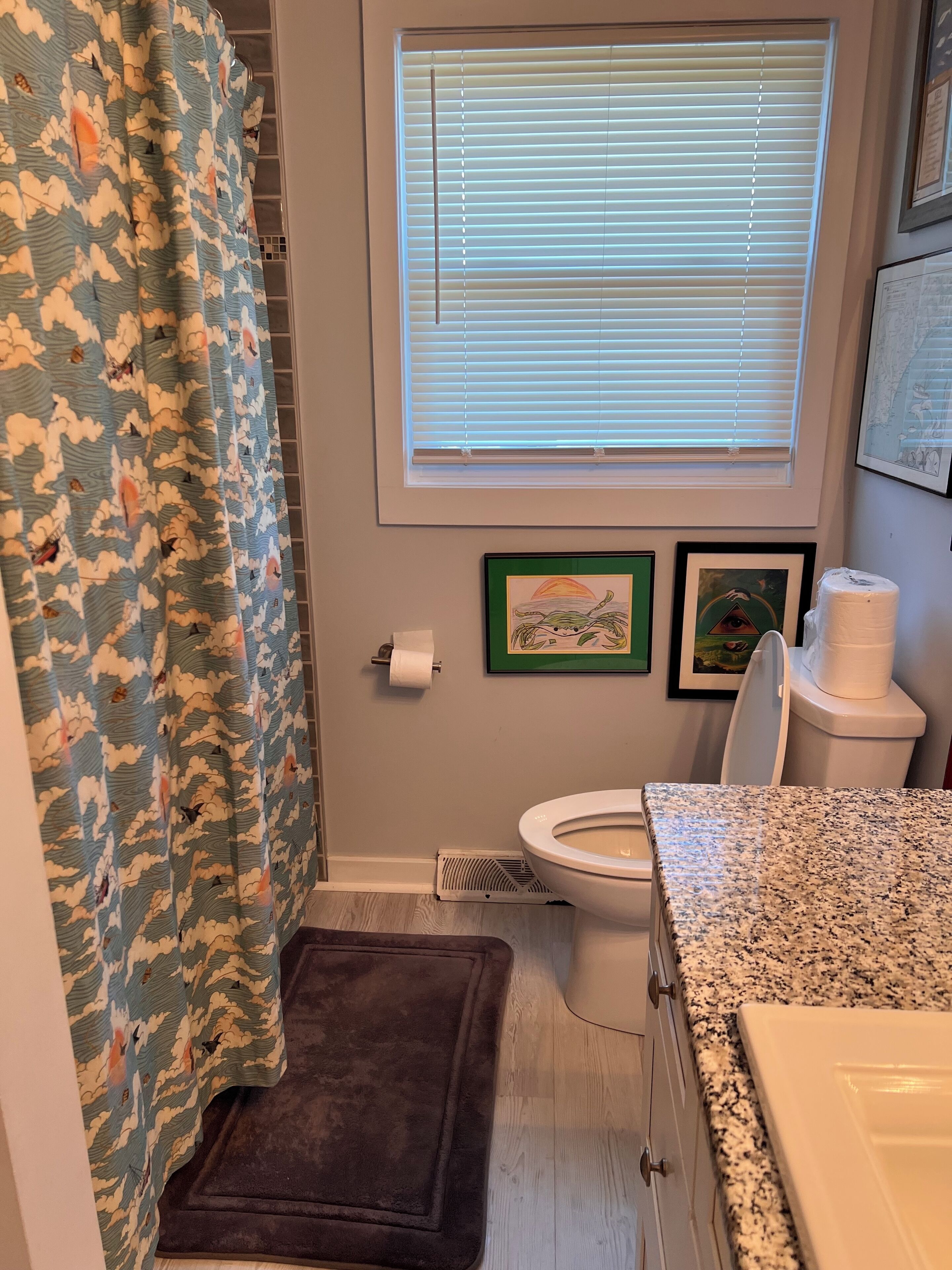 A bathroom with a shower curtain, toilet, and sink.