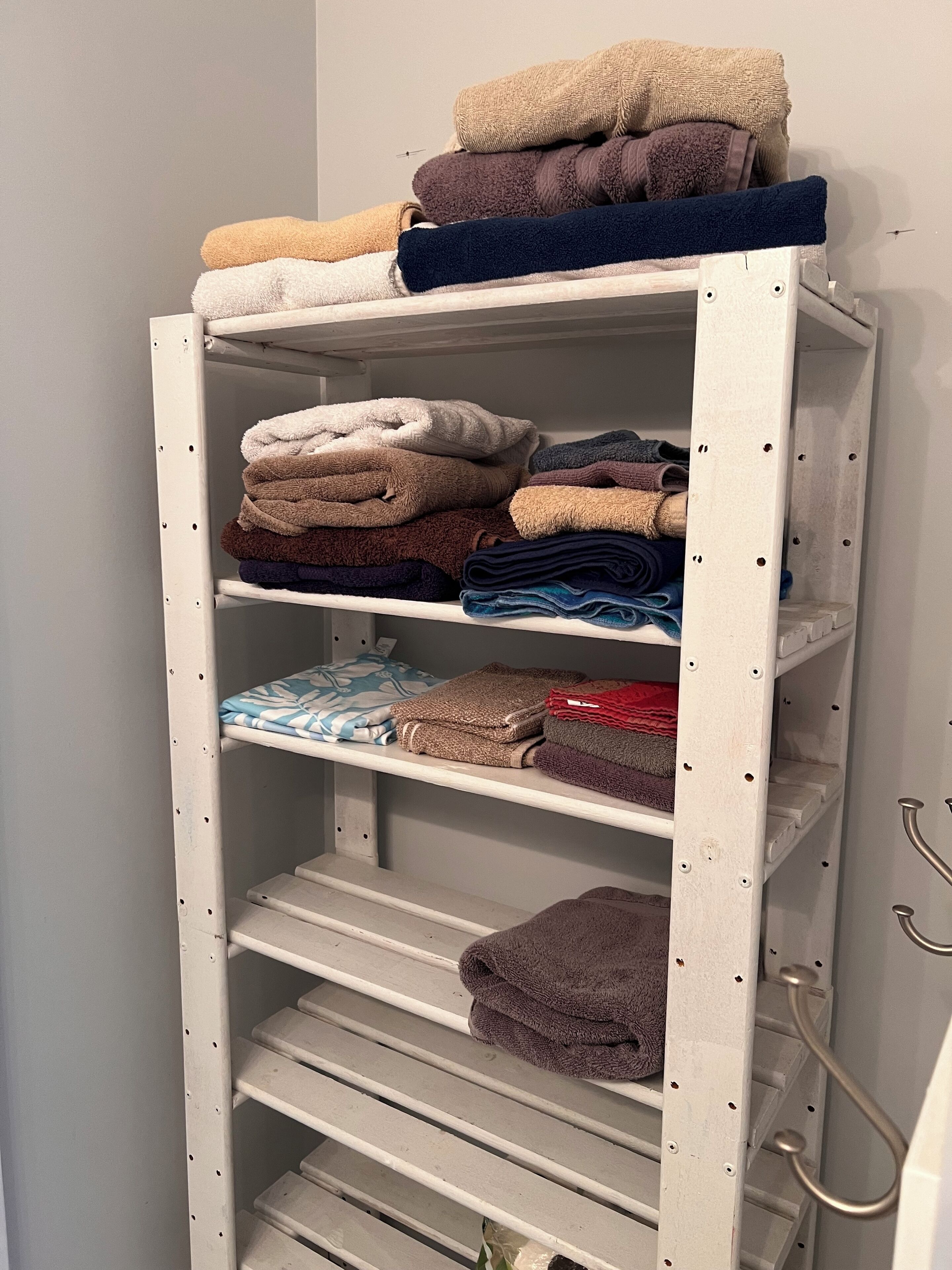A metal storage unit with multiple shelves holding folded towels in various colors.