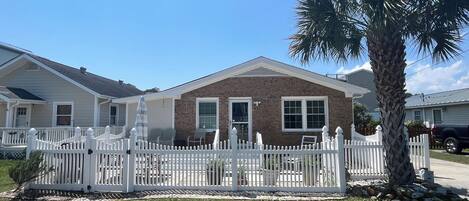 A two-story house with a brick facade, white trim, and a white picket fence.