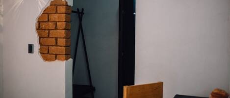A room with a brick wall feature, a door, a tripod, and a small table.