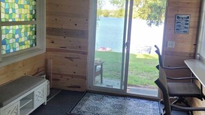 A cabin with a wooden interior, a glass door leading outside, a bench, and a table. - Lake Front on Little Clear Lake- Comfort Resort (Prescott)