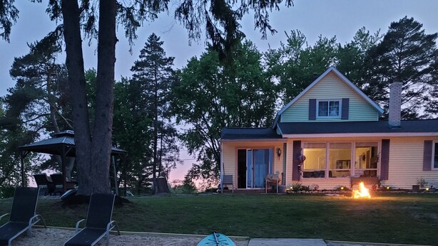 A lakeside property with a dock, a boat, and a house with a fire in the background. - Lake Front on Little Clear Lake- Comfort Resort (Prescott)