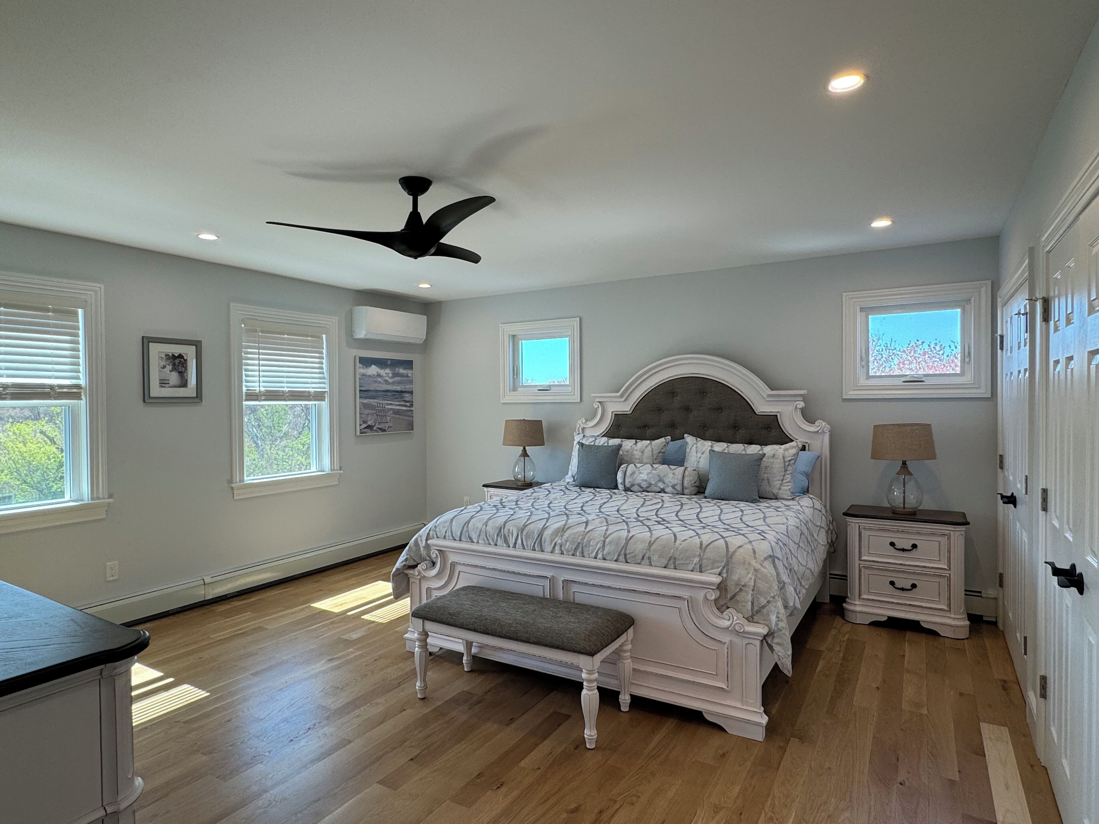 Quarto com uma cama grande, ventilador de teto e janela com vista para o céu.