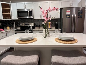 A modern kitchen with white cabinets, stainless steel appliances, and a central island with two seating areas. - King Bed • Pool • Fast Wi-Fi • W/D • Workspace (Dallas)