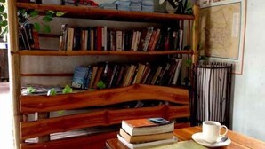 Un banc en bois, avec des livres, une carte et une tasse posés sur une table.