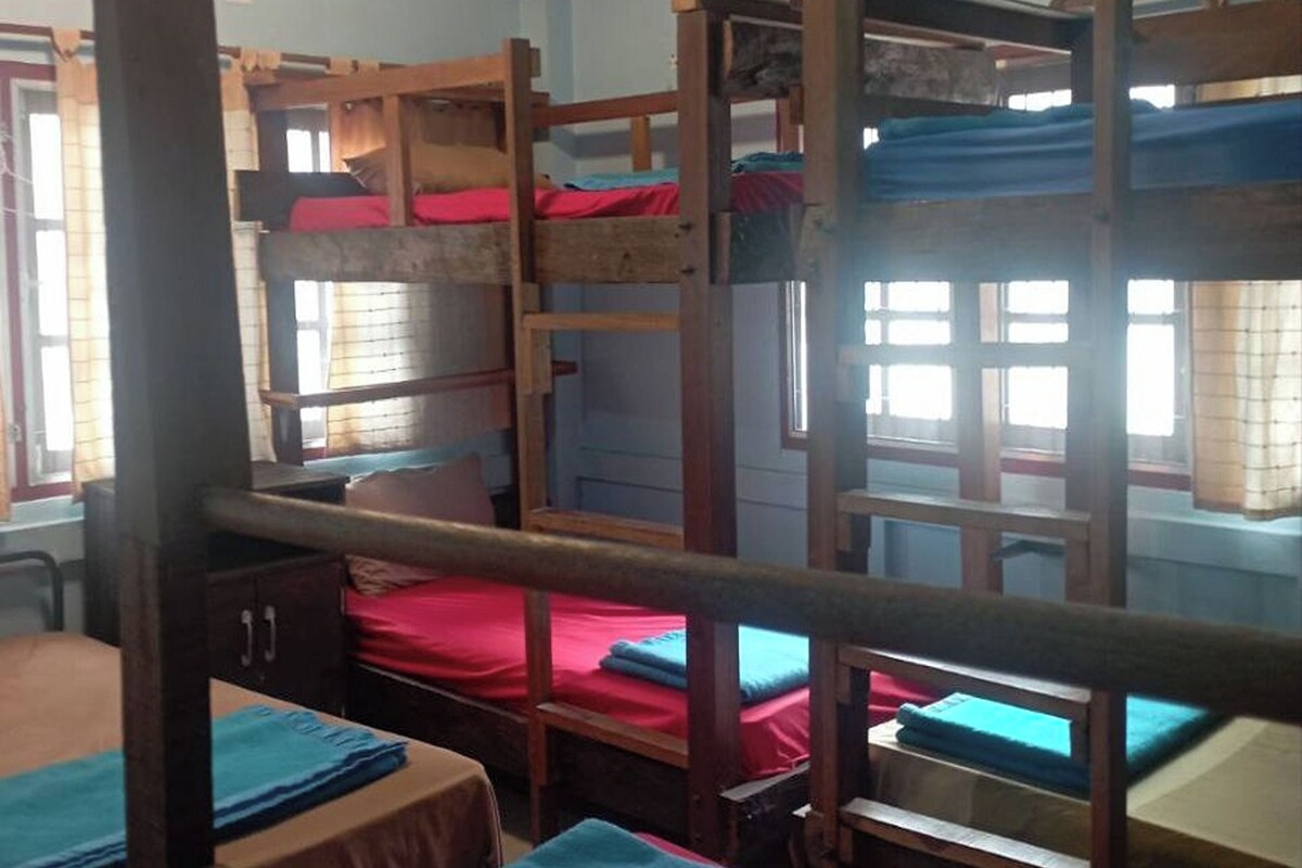 Une chambre de dortoir avec des lits superposés, des bureaux en bois et des draps rouges.