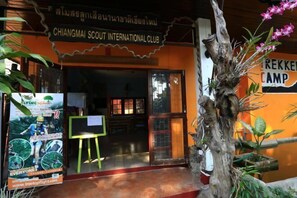 L'ingresso del Chiangmai Scout International Club con una scultura di albero in legno e un manifesto che pubblicizza esperienze di volo tra gli alberi.