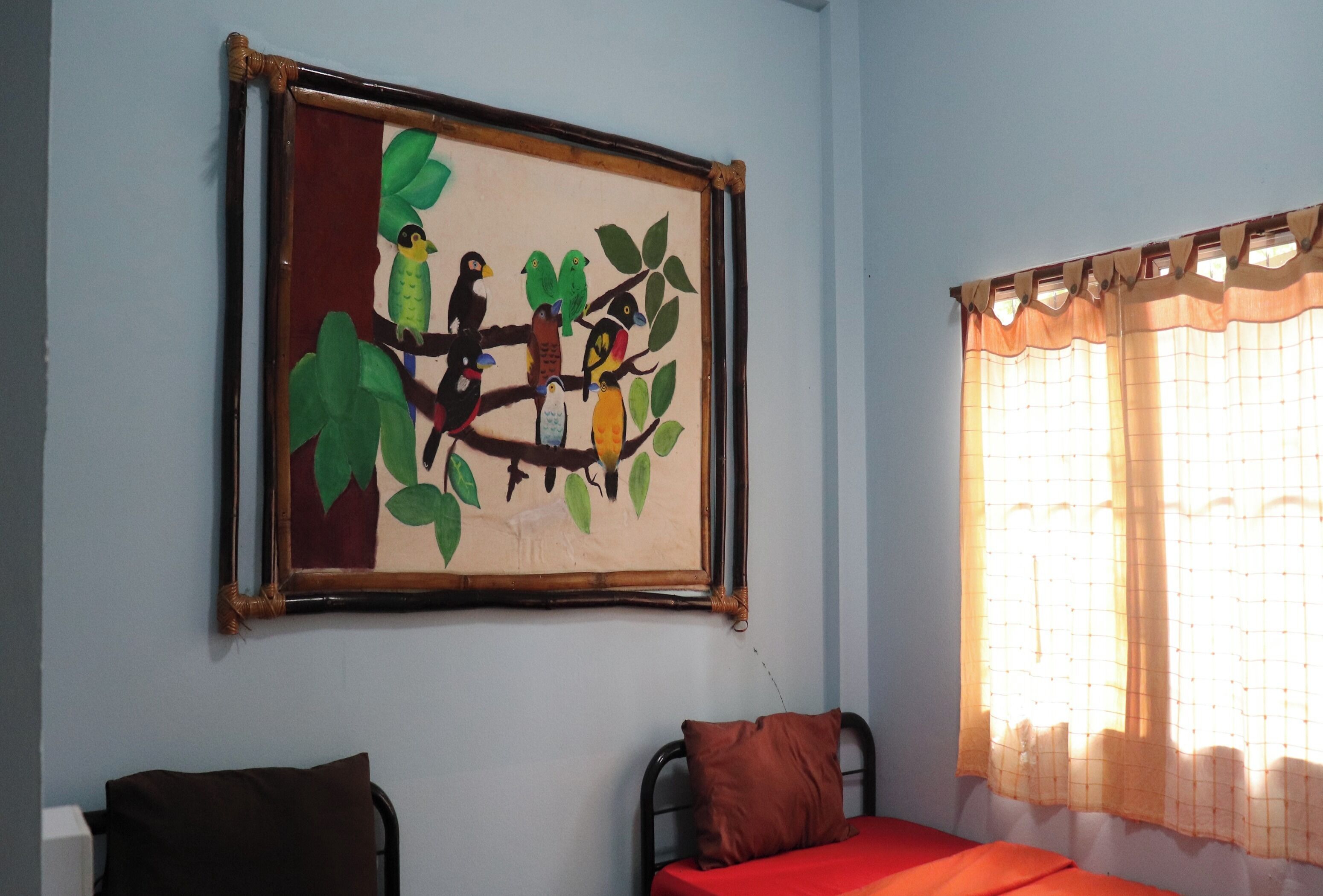 Une pièce comprenant un lit, une chaise et un tableau représentant des oiseaux perchés sur une branche, accroché au mur.