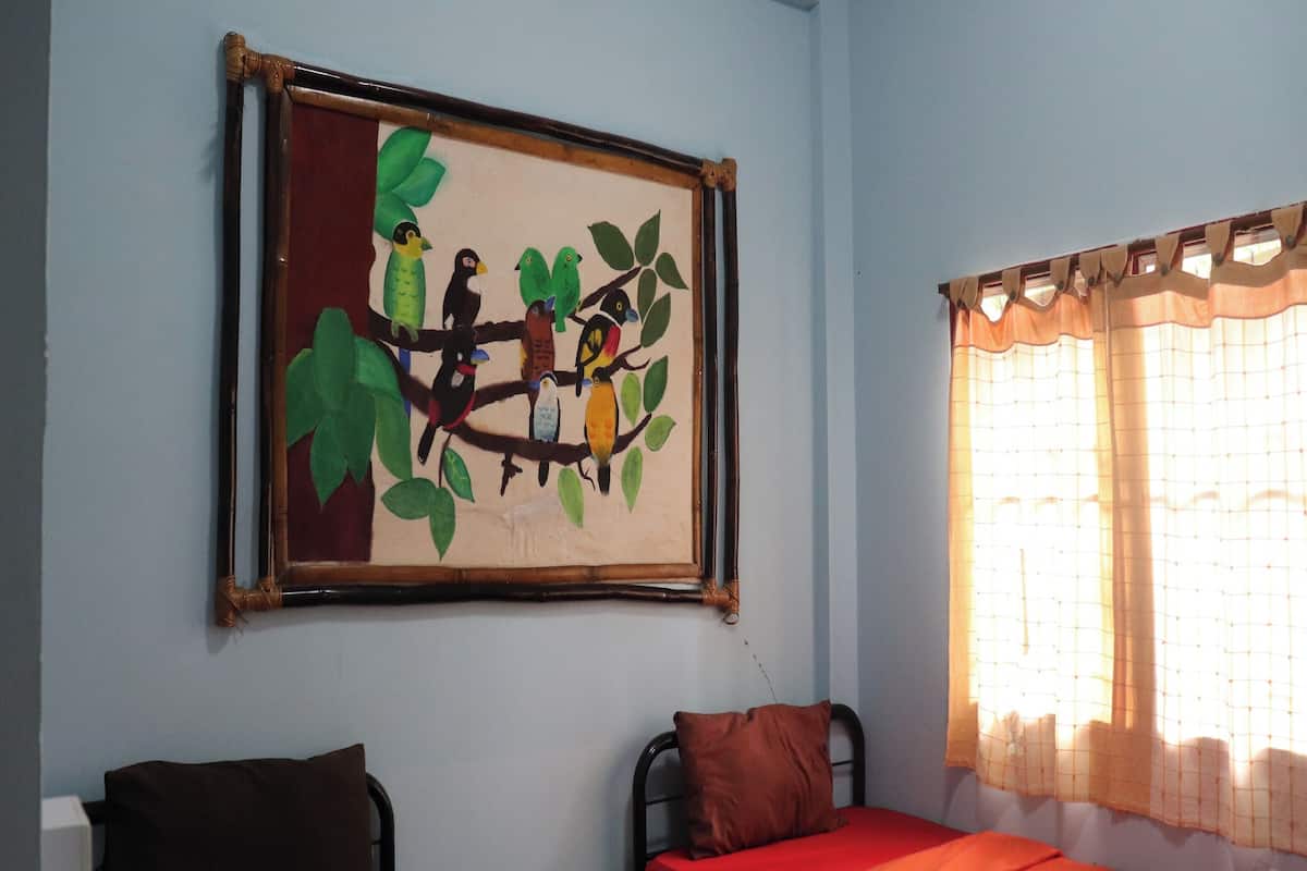 Een kamer met een bed, een stoel en een wanddecoratie van vogels op een tak.
