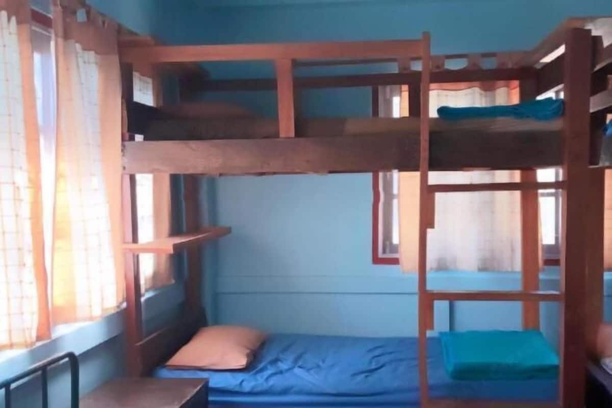 Een slaapkamer met stapelbed, raam, gordijnen en bureau.