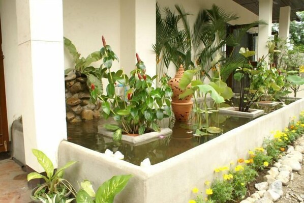 Un giardino interno sereno con diverse piante in vaso e un piccolo elemento d'acqua.