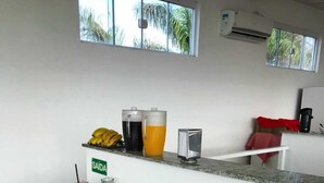 A buffet with various food items and beverages, including bread, pastries, and a juice dispenser. - Pousada Mar Alto (Ilha Comprida)