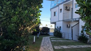 A modern building with a stone pathway leading to a glass entrance. - Pousada Mar Alto (Ilha Comprida)