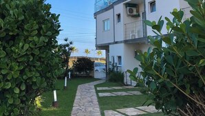 A modern building with a glass facade, a stone pathway, and lush greenery. - Pousada Mar Alto (Ilha Comprida)