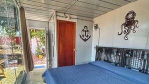 A bedroom with a large bed, a wooden door, and a view through a glass door.