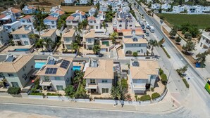 A residential area with modern houses, a road, and a green space. - Villa Amesta - Private Pool Retreat (Protaras)