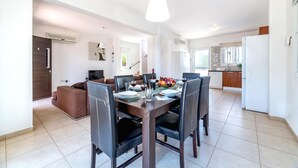 A modern dining area with a wooden table set for six, surrounded by black chairs. - Villa Amesta - Private Pool Retreat (Protaras)