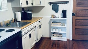 A kitchen with white cabinets, a wooden countertop, a stove, and a coffee maker. - Cozy studio rental situated between Bedford and Lynchburg Virginia (Forest)