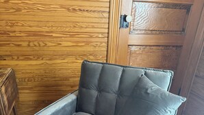A grey upholstered armchair with a cushioned backrest and armrests, positioned on a wooden floor. - Cozy studio rental situated between Bedford and Lynchburg Virginia (Forest)