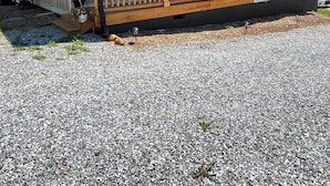 Une maison de plain-pied dotée d’un porche couvert, d’un petit garage attenant et d’une allée en gravier.