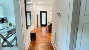 Un couloir doté d’un plancher en bois, de murs blancs et d’un plafond avec des poutres apparentes.