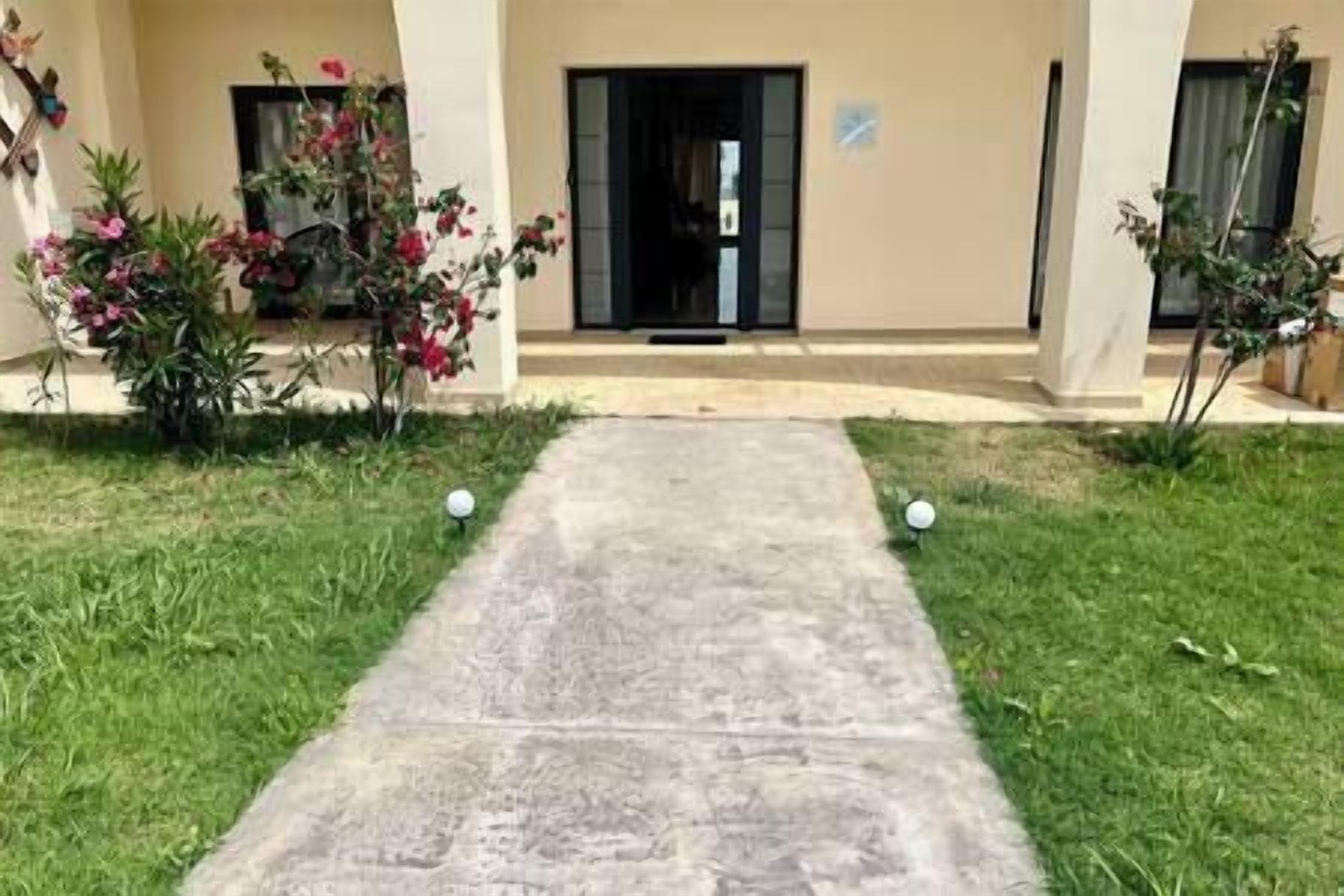 Uma passagem leva a uma entrada de prédio, com uma porta e uma pequena placa acima.