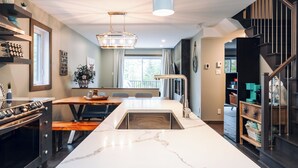 Eine moderne Küche mit Kochinsel, Backofen und Essbereich mit einer Bank.