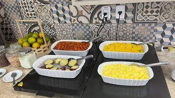 A buffet table with various dishes, including a casserole with carrots, a dish with yellow rice, and a dish with sliced potatoes.