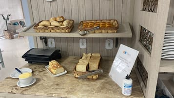 Desayuno buffet con pan, bollería y un cartel sobre el consumo de alcohol.
