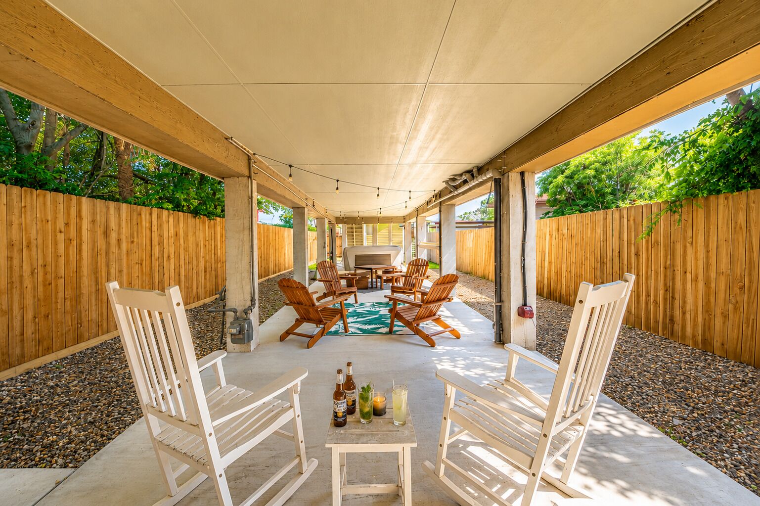 An outdoor patio with wooden chairs, a table, and a grill.
