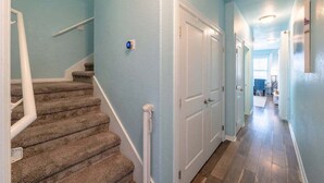 A hallway with carpeted stairs, white doors, and a light blue wall.