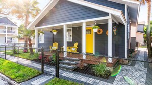 A house with a dark exterior, a porch with yellow chairs, and a yellow door. - Historic Cottage Walk to Downtown St Augustine Free Parking Sleeps 4 (St. Augustine)