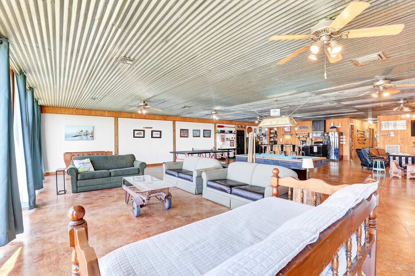A spacious living area with a large bed, multiple seating options, a pool table, and a bar area.