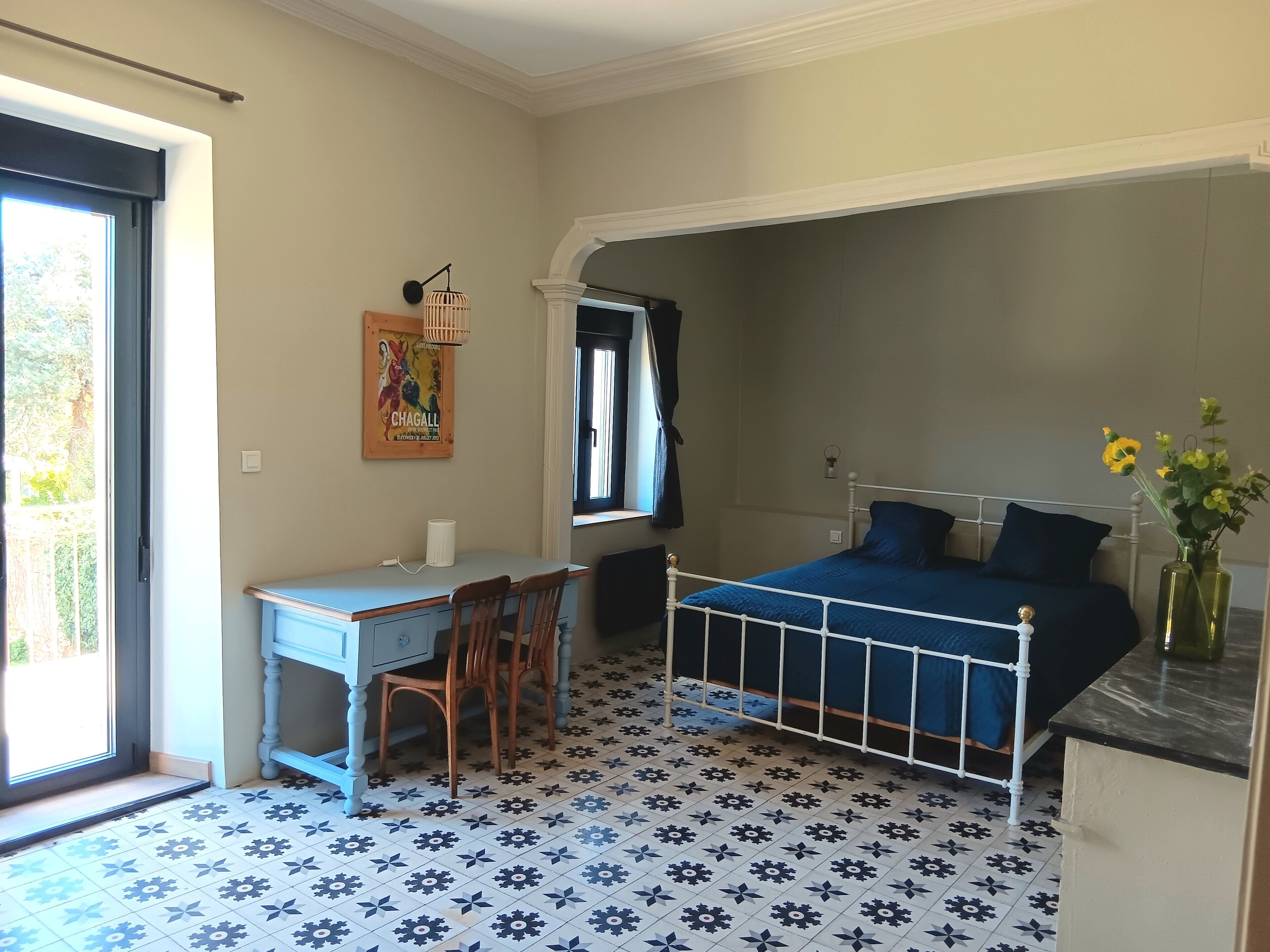 A bedroom with a bed, a desk, and chairs.