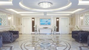 A spacious lobby with a marble floor, a central chandelier, and two sofas. - Bellicity Apart Complex (Ravda)