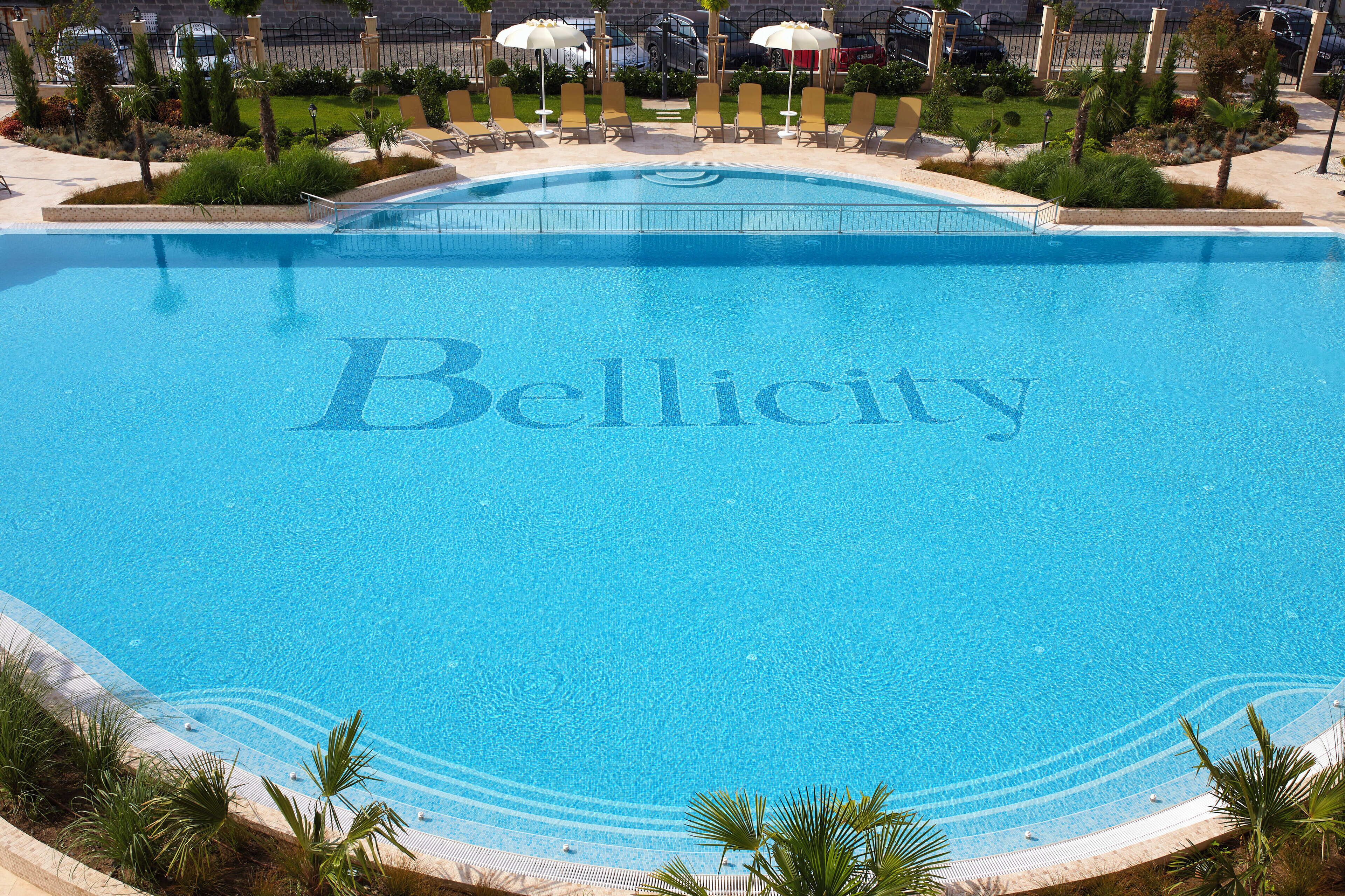 A large, clear swimming pool with the word "Bellcity" written in the center.
