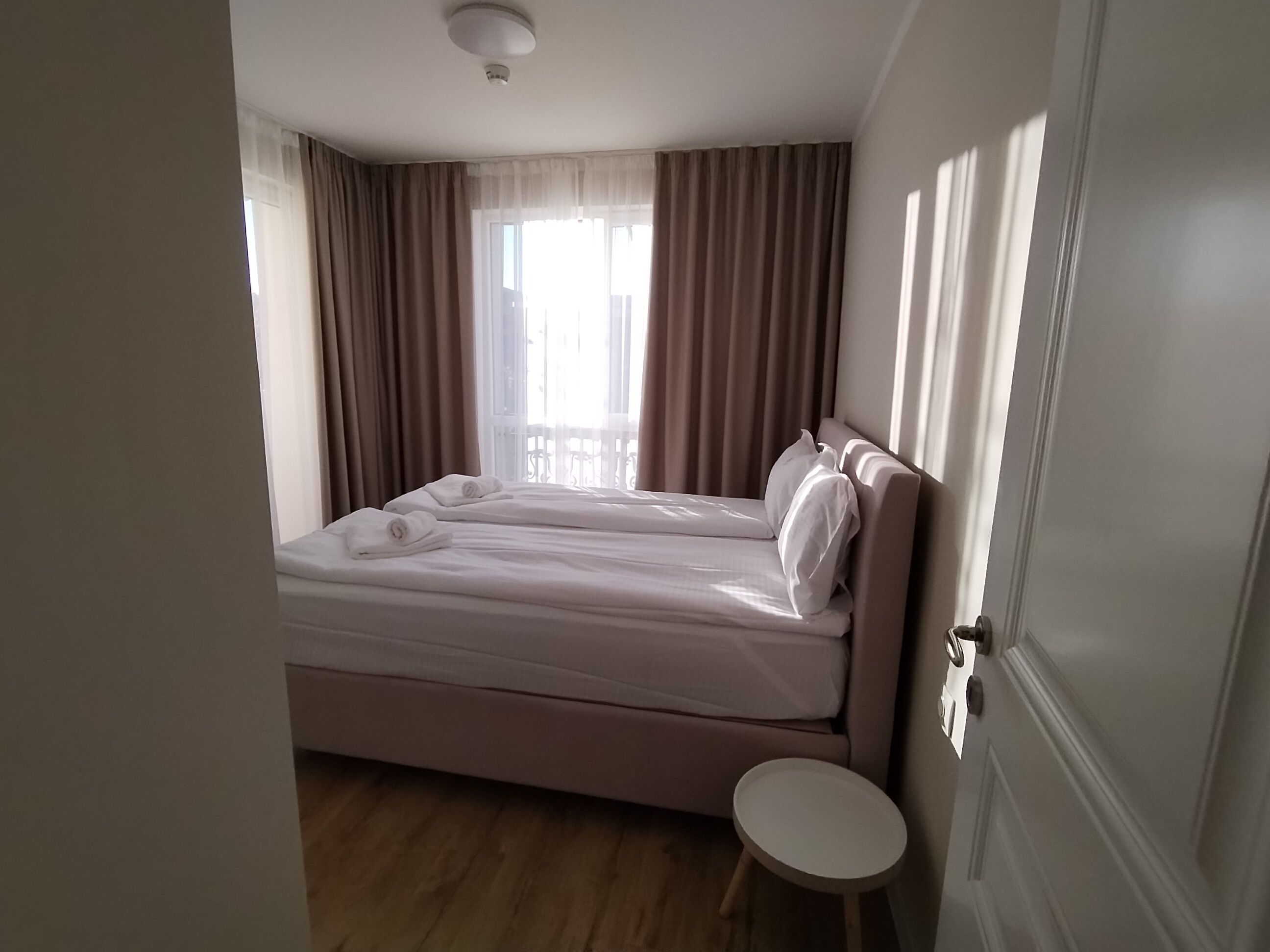 Une chambre d’hôtel avec un lit, une petite table ronde et une porte.