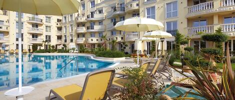Un hotel con piscina, tumbonas y sombrillas.