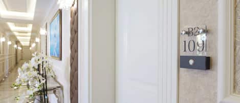 A hallway with a sign reading "B2 109" on the wall, a vase with white flowers, and a framed picture on the wall.