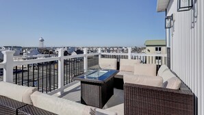 Une terrasse sur le toit avec une table à plateau de verre, des meubles en osier et une vue sur le paysage urbain.