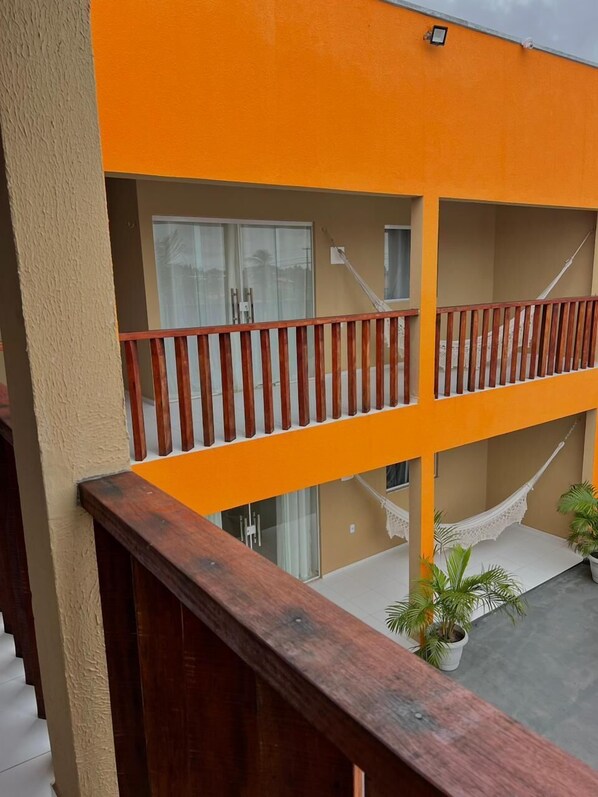 A multi-level building with orange and beige exterior walls, wooden railings, and a hammock.