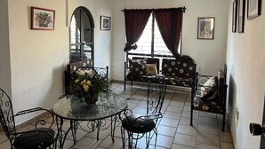 A dining area with a glass table, black metal chairs, a sofa with floral upholstery, and a ceiling fan. - Casa Los Angeles  (Colima)