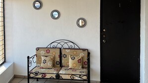 A room with a black door, a sofa with floral upholstery, and three wall-mounted mirrors. - Casa Los Angeles  (Colima)