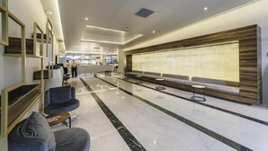 A modern lobby with a marble floor, seating areas, and a reception desk. - orbi city 777 (Batumi)