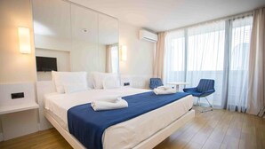 A hotel room with a large bed, a small table, a chair, and a large window with curtains. - orbi city 777 (Batumi)
