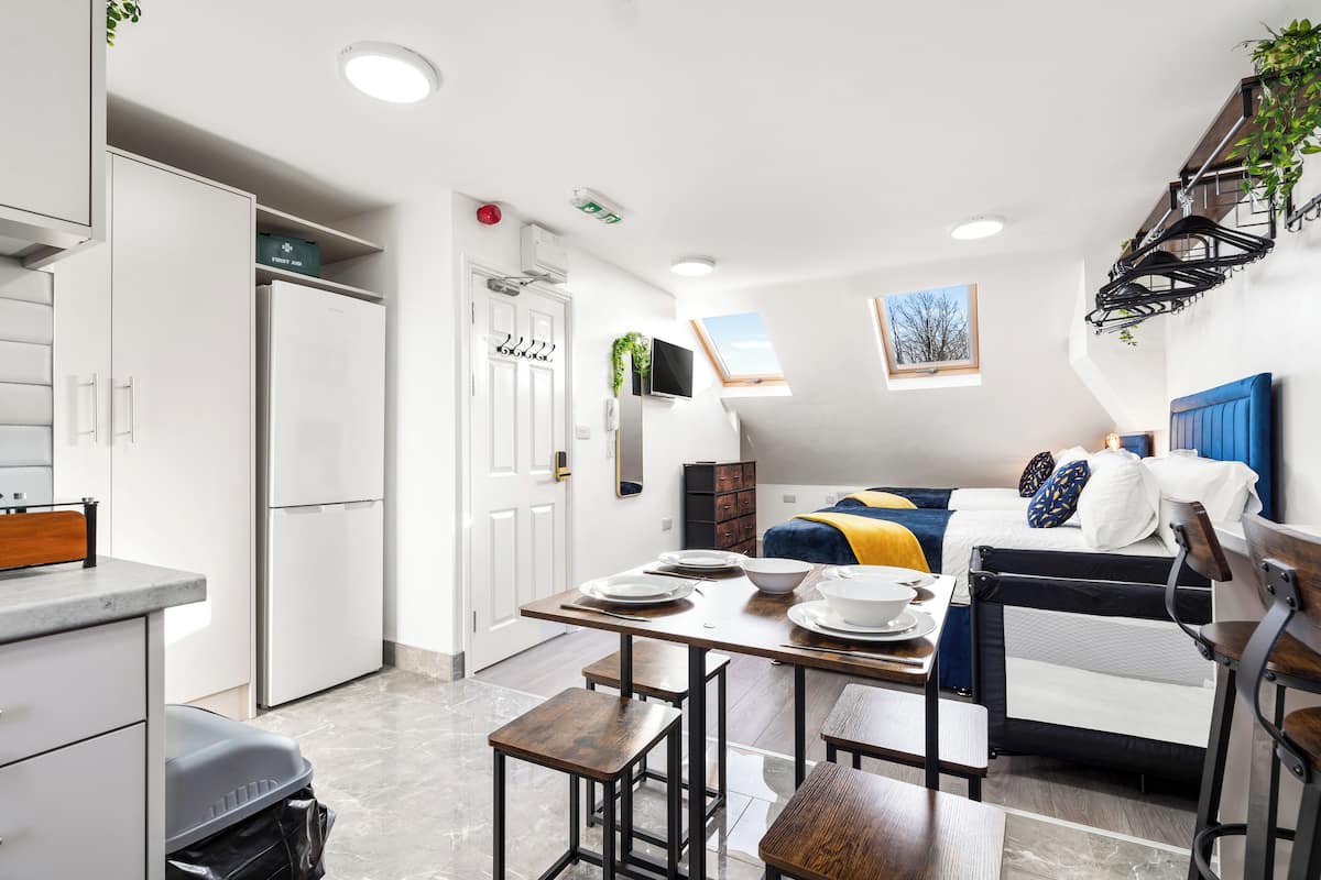 A compact living space with a kitchenette, a dining area, and a bed.