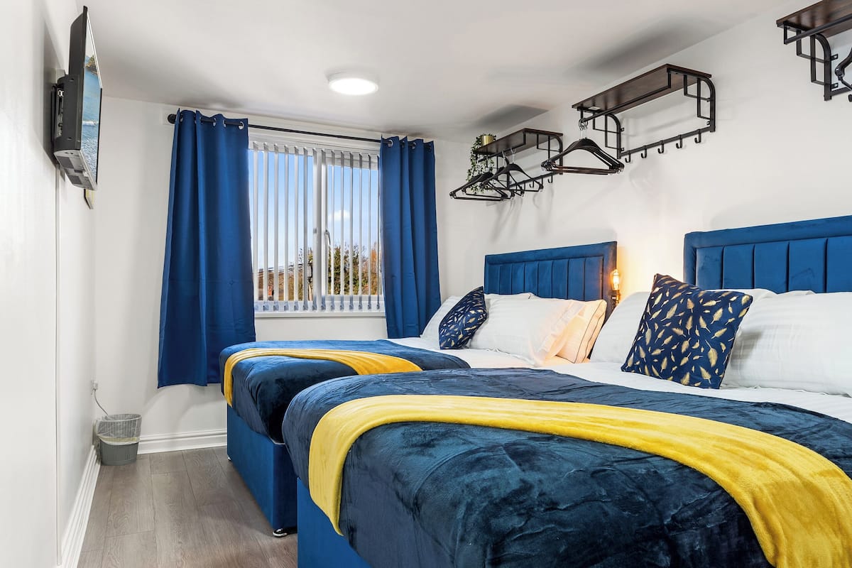A hotel room with two beds, a TV, a window with curtains, and a ceiling light.